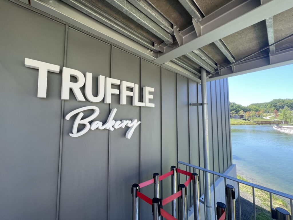TRUFFLE Bakery のロゴサインと、右手に広がる池と対岸の緑
