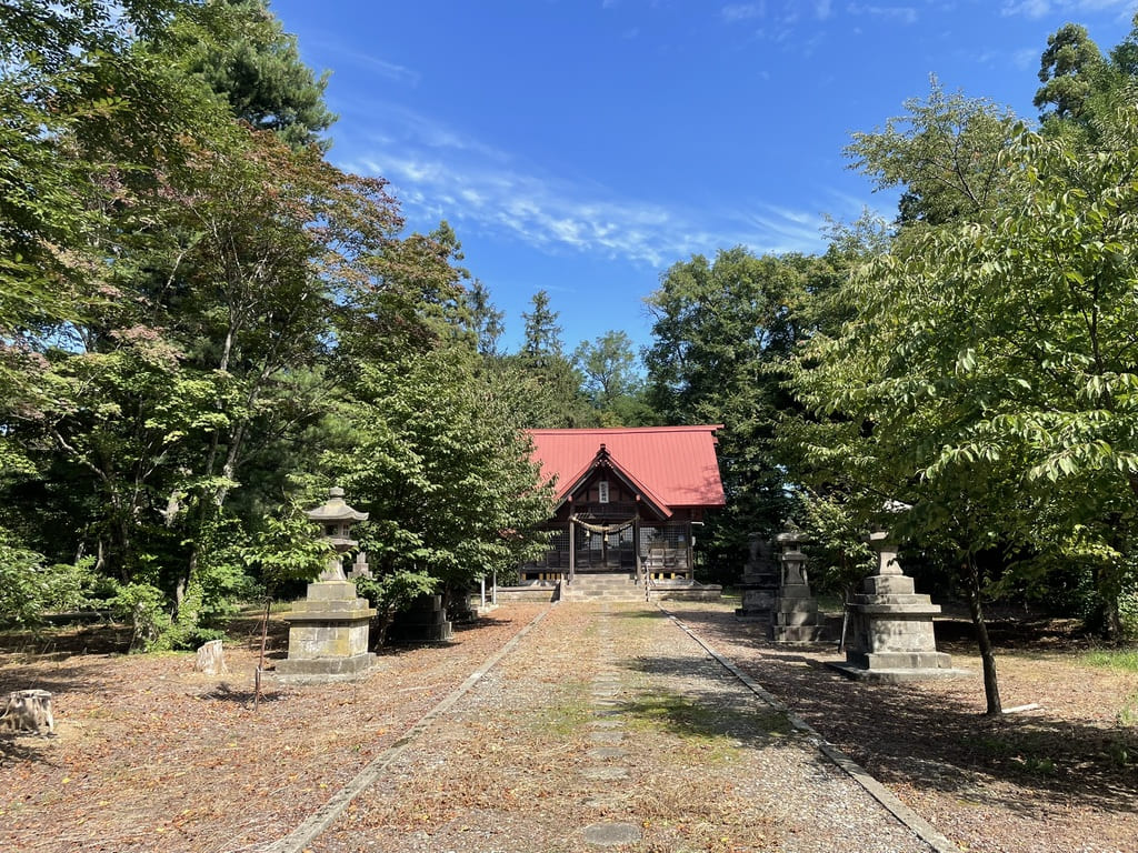 木々と石灯籠に囲まれた札比内神社の参道と社殿