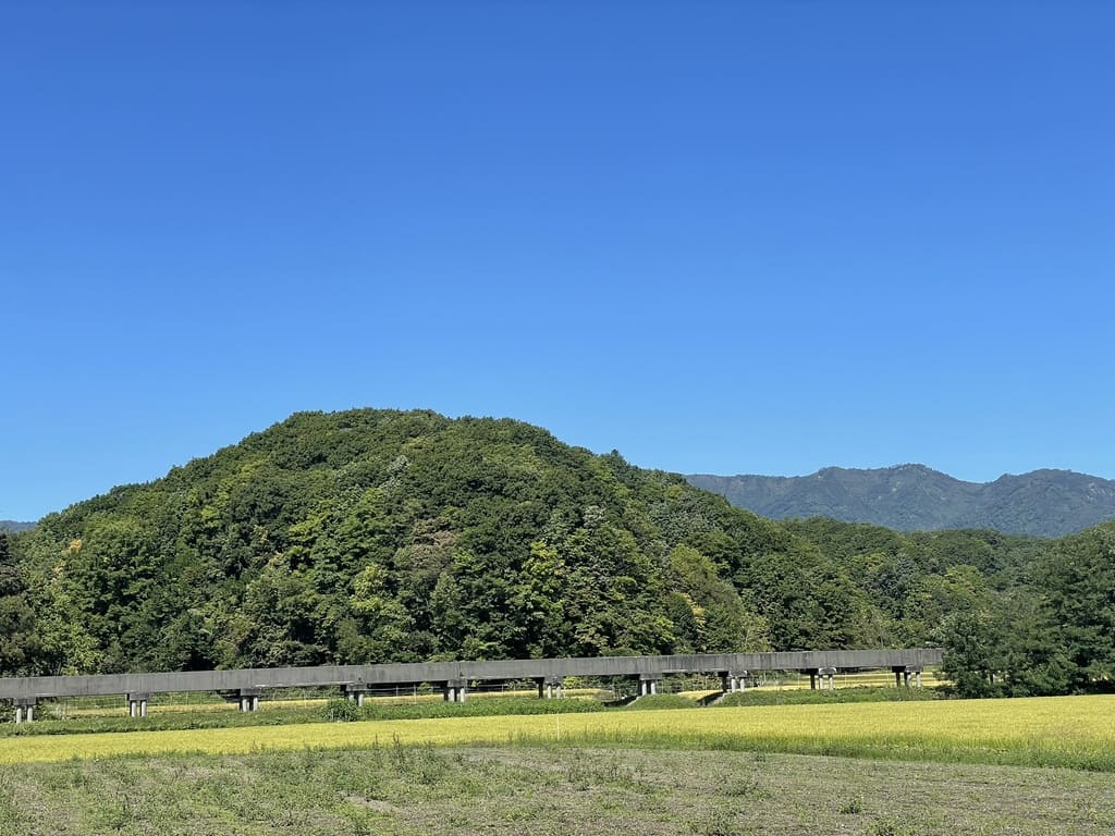 札比内地区の農地越しに見える山並みとコンクリート構造物