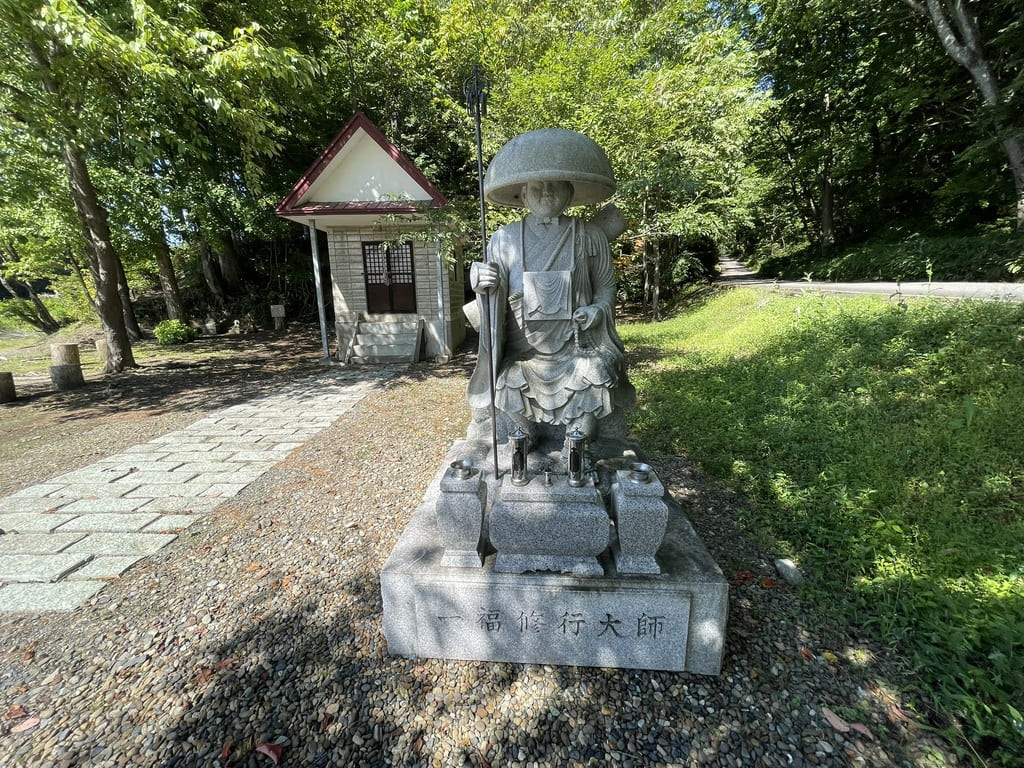 聖天堂と森へ続く道を背にした一福修行大師像