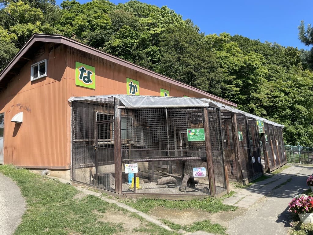 緑色の動物解説板が並ぶ栗山公園なかよし動物園の飼育舎
