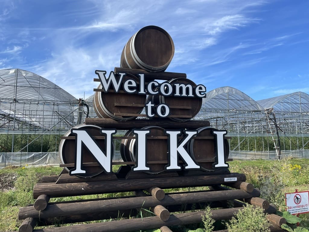 果樹ハウスを背景に設置されたWelcome to NIKIのモニュメント