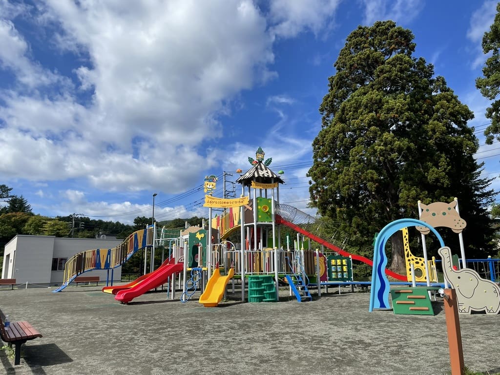 芝生に大型複合遊具があるふるびら150年広場の全景