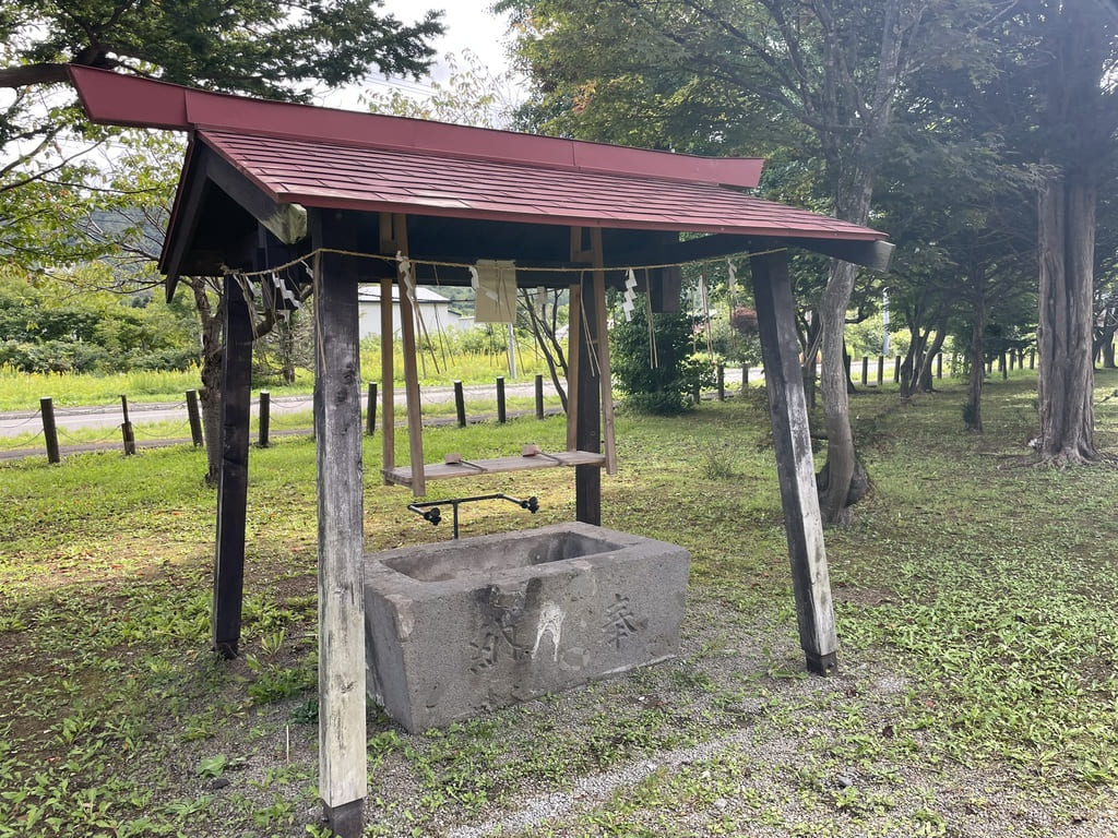 木造の屋根と石造水盤がある美国神社の手水舎