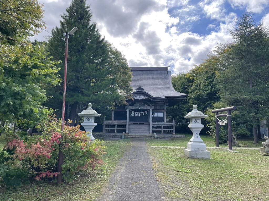 石灯籠と木々の奥に美国神社拝殿が見える境内全景