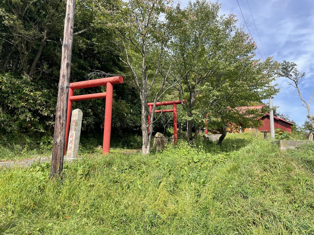 道路側から見た幌武意稲荷神社の鳥居と草が伸びた境内