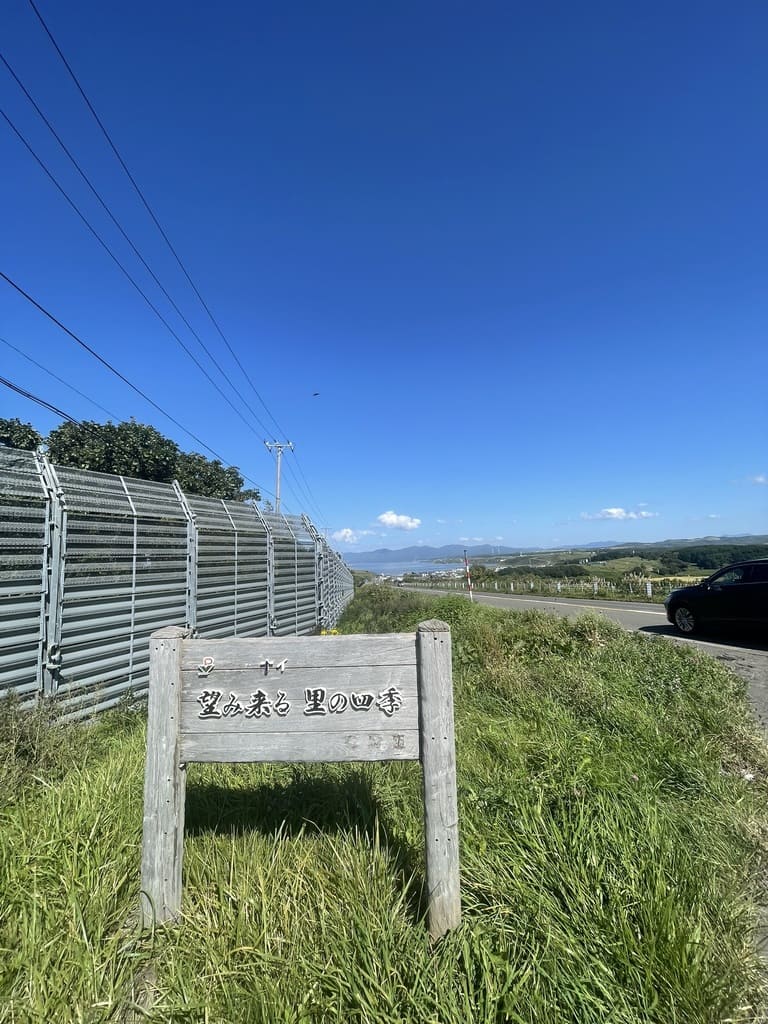 「望み来る 里の四季」の看板と望来方面へ続く国道231号の景色