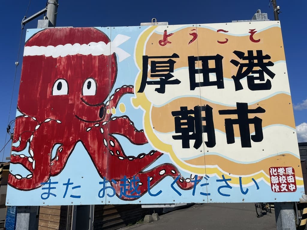 タコのイラストが描かれた「ようこそ厚田港朝市」の看板