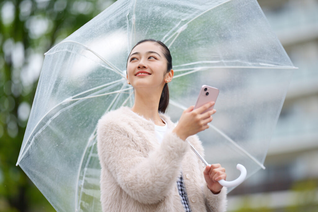 傘を差してスマホで検索をする人